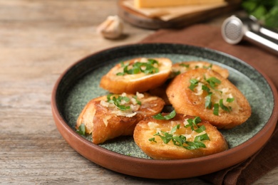 Photo of Slices of toasted bread with garlic, cheese and herbs on wooden table