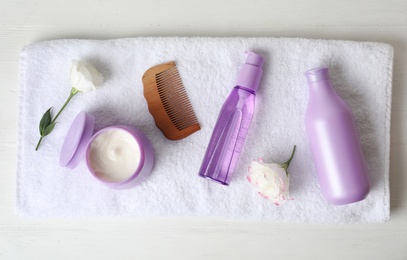 Photo of Different hair products, towel and comb on white wooden table, top view