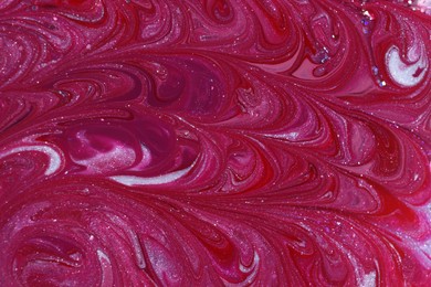 Photo of Mixed different color nail polishes with glitter as background, top view