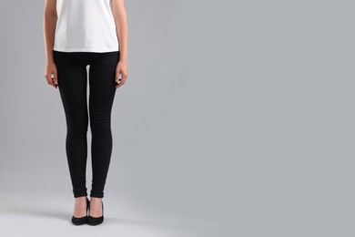 Photo of Woman wearing stylish black jeans and high heels shoes on light gray background, closeup. Space for text