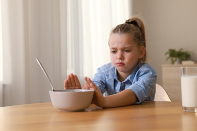 Photo of Cute little girl refusing to eat her breakfast at home