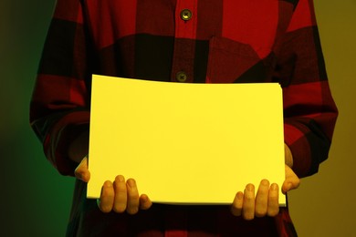 Photo of Man holding sheets of paper on dark background, closeup and space for text. Color tone effect