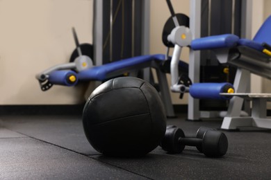 Photo of Black medicine ball and dumbbells on floor in gym