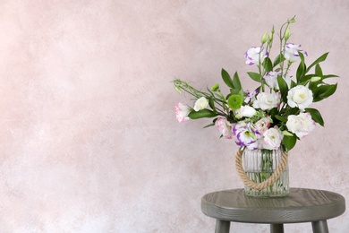 Photo of Vase with bouquet of beautiful flowers on table against color background. Space for text