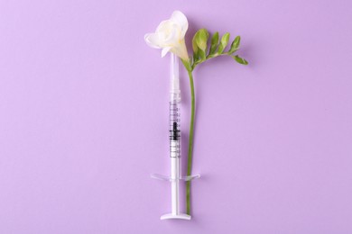Photo of Cosmetology. Medical syringe and freesia flower on violet background, top view