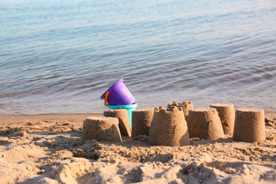 Photo of Little sand figures and plastic toys on beach near sea. Space for text