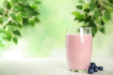 Tasty fresh milk shake and blueberries on white table. Space for text