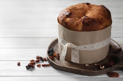 Photo of Delicious Panettone cake, walnuts and raisins on white wooden table, space for text. Traditional Italian pastry
