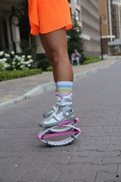 Sporty woman doing exercises in kangoo jumping boots outdoors, closeup