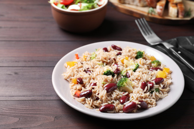 Photo of Delicious rice with beans served on wooden table