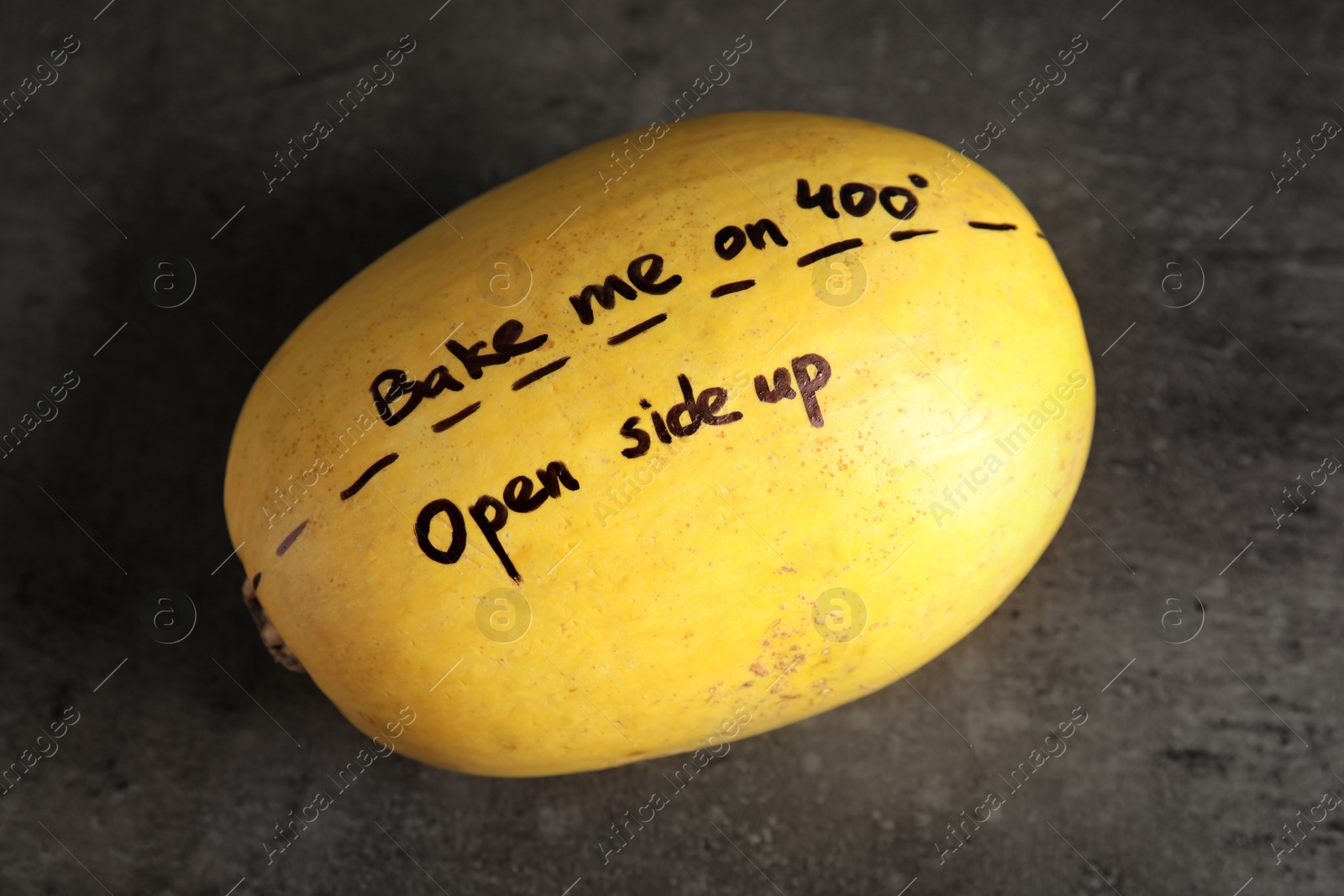 Photo of Ripe spaghetti squash with cooking instructions on gray table