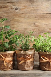 Different aromatic potted herbs on wooden table