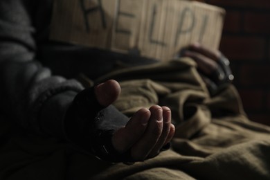 Poor homeless man with help sign begging for money, closeup. Charity and donation