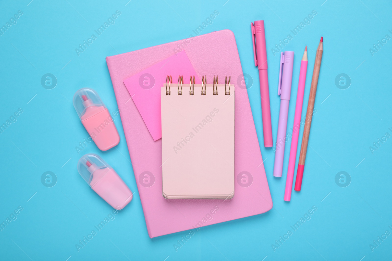 Photo of Flat lay composition with pink notebooks and other school stationery on light blue background, space for text. Back to school