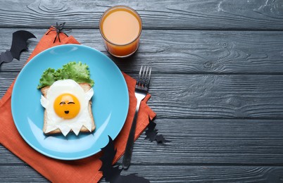 Photo of Halloween themed breakfast served on black wooden table, flat lay and space for text. Tasty toast with fried egg in shape of ghost