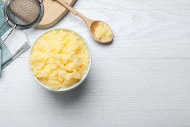 Photo of Bowl and spoon of Ghee butter on white wooden table, flat lay. Space for text