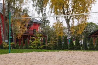 Photo of Sand volleyball court with net near trees and buildings