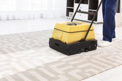 Photo of Male worker with carpet cleaner indoors, closeup