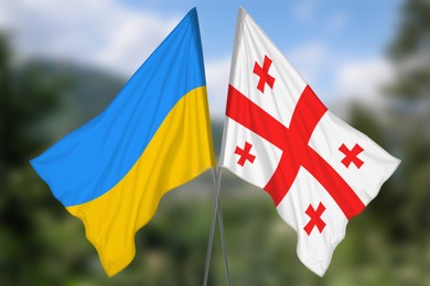 Image of National flags of Ukraine and Georgia against blurred landscape