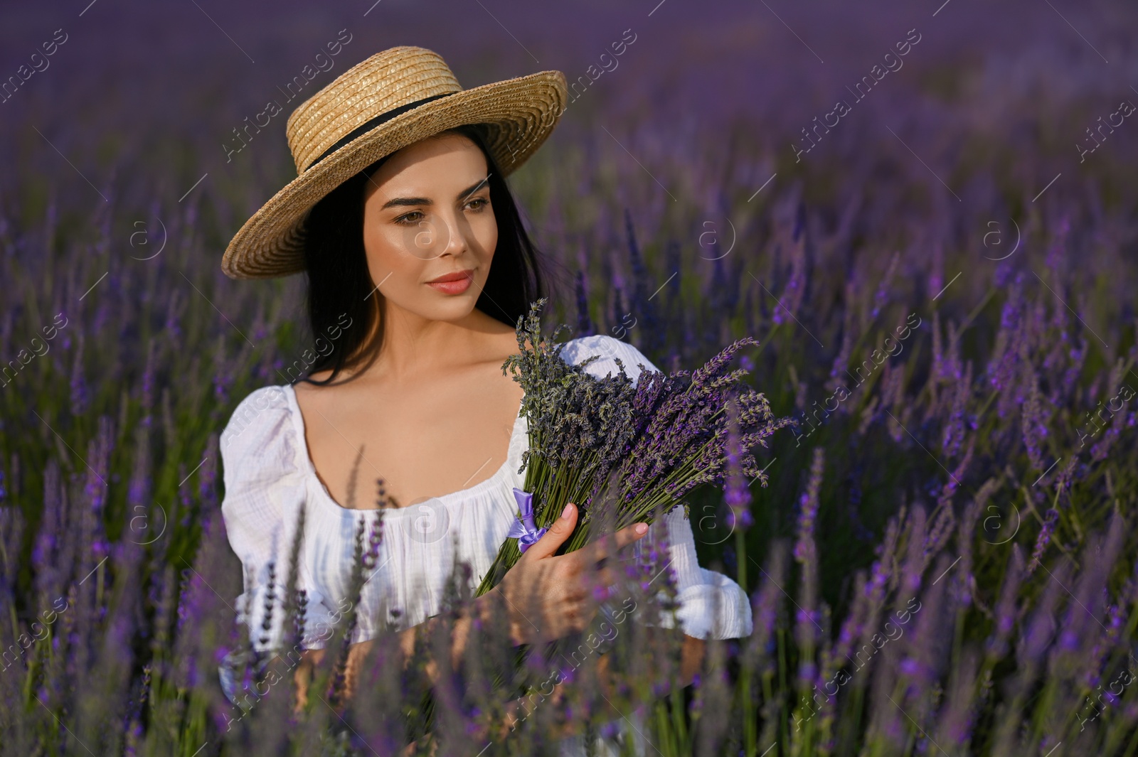 Photo of Beautiful young woman with bouquet in lavender field