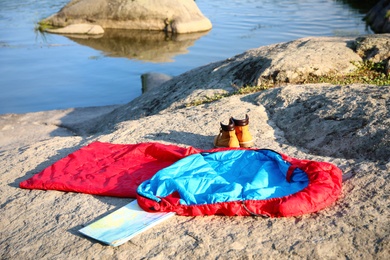 Photo of Sleeping bag, boots and map outdoors on sunny day