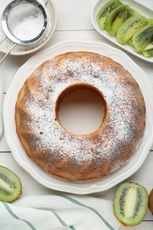 Photo of Homemade yogurt cake with kiwi and powdered sugar on white wooden table, flat lay