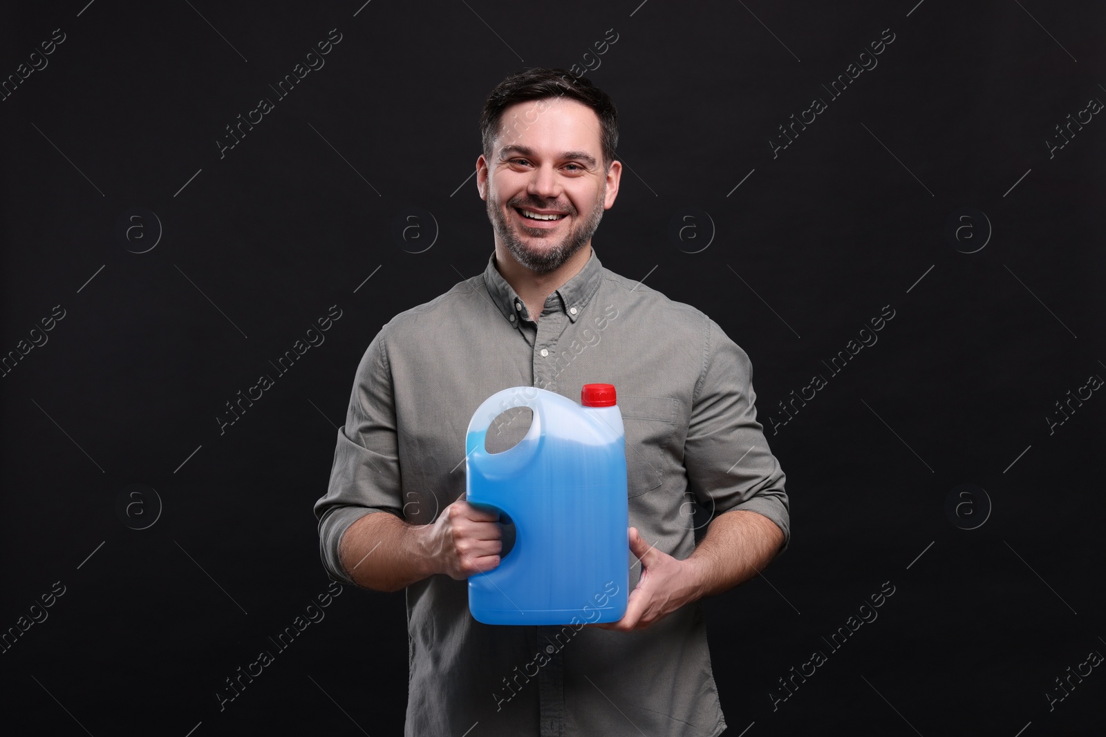 Photo of Man holding canister with blue liquid on black background