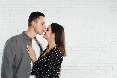 Photo of Happy young couple near white brick wall. Space for text