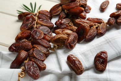 Photo of Tasty sweet dried dates and green leaf on white wooden table, closeup