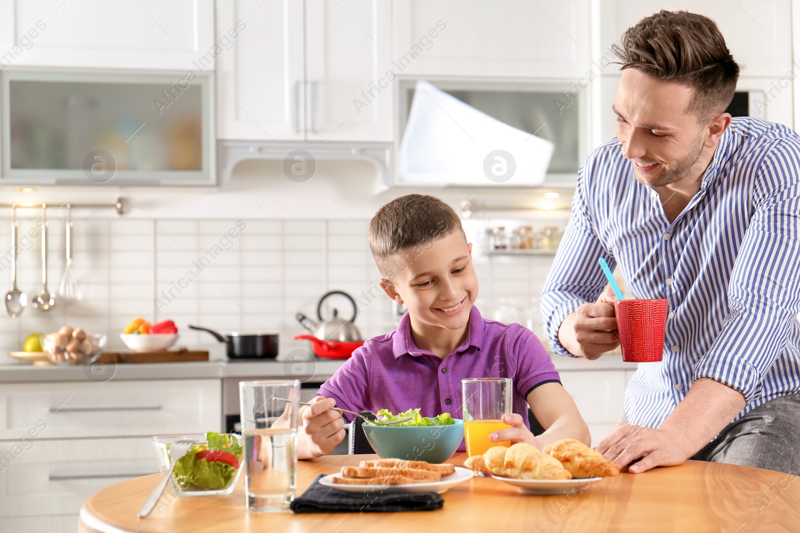 Photo of Dad and son having breakfast together in kitchen