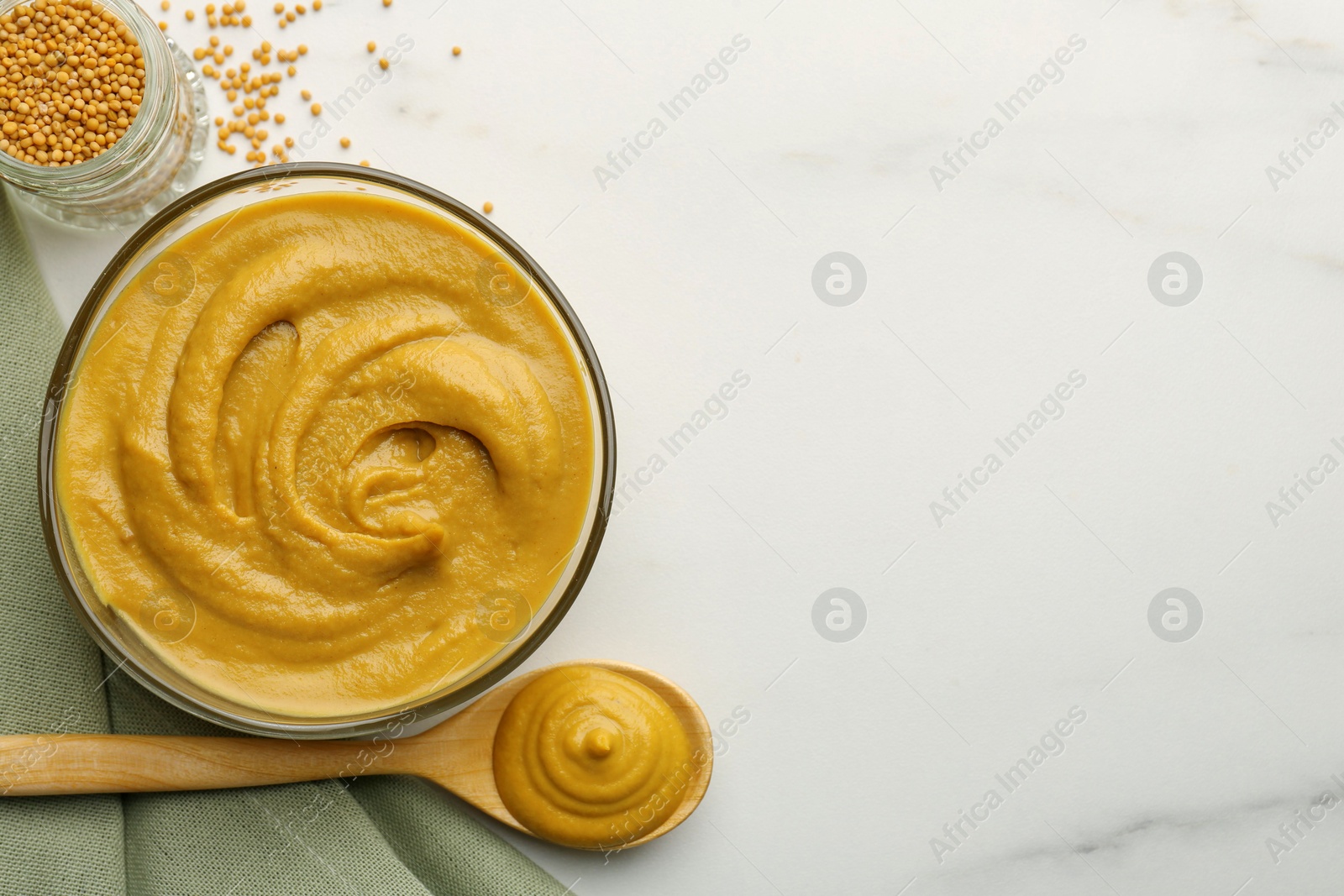 Photo of Tasty mustard sauce and dry seeds on white marble table, flat lay. Space for text