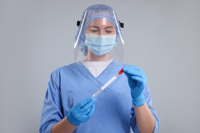 Photo of Laboratory testing. Doctor with cotton swab and tube on light grey background