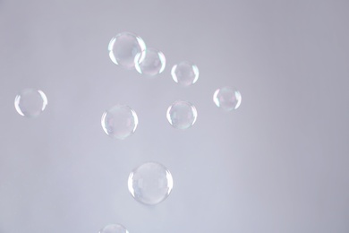 Photo of Beautiful translucent soap bubbles on grey background