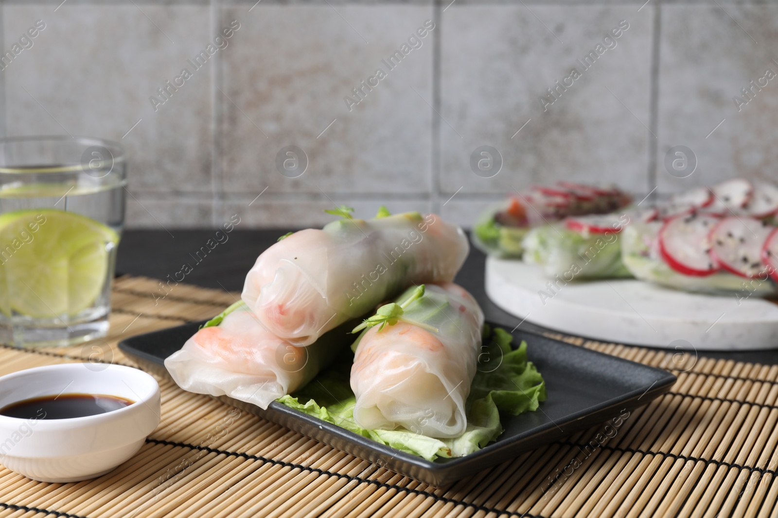 Photo of Delicious spring rolls and soy sauce on table