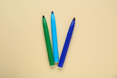 Different colorful markers on beige background, flat lay