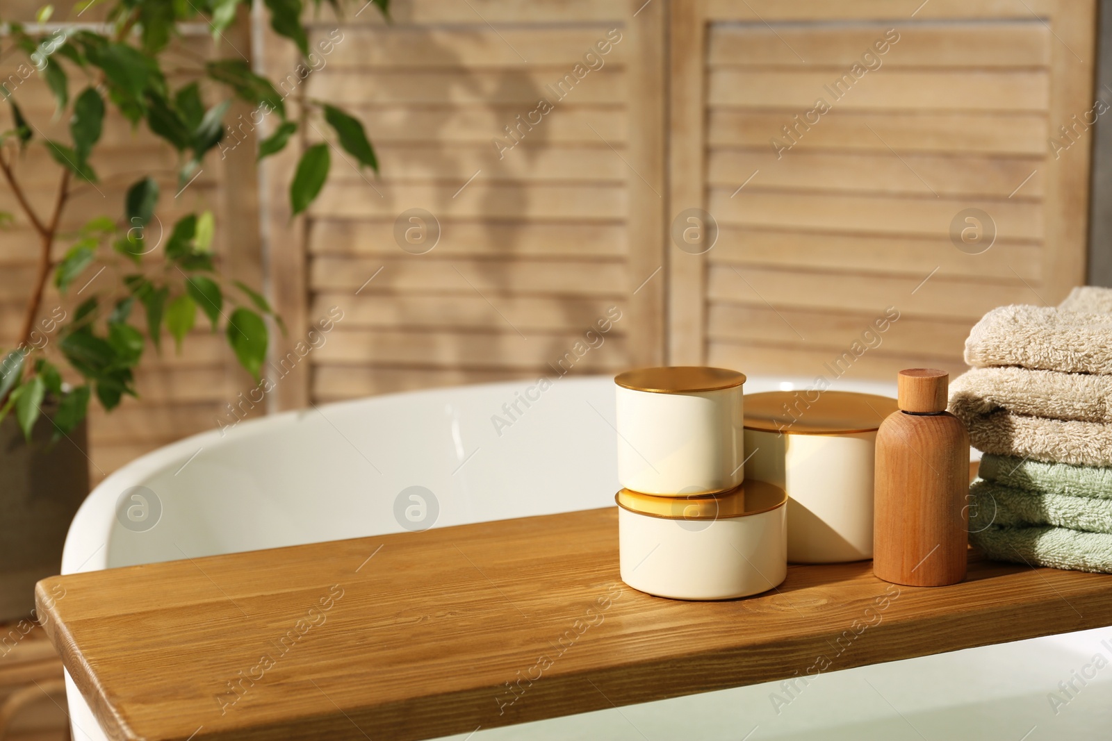 Photo of Wooden tray with spa products and towels on bath tub in bathroom. Space for text