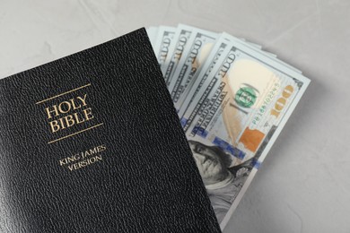 Photo of Holy Bible and money on grey table, top view