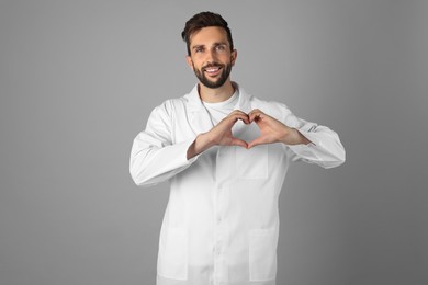 Photo of Doctor making heart with hands on grey background