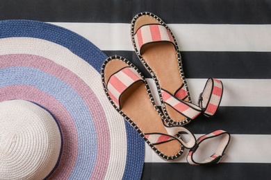 Pair of female shoes and hat on striped background