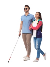 Photo of Young woman helping blind person with long cane on white background
