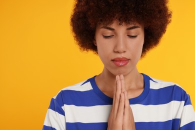 Photo of Woman with clasped hands praying to God on orange background