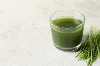 Photo of Wheat grass drink in glass and fresh sprouts on light table. Space for text