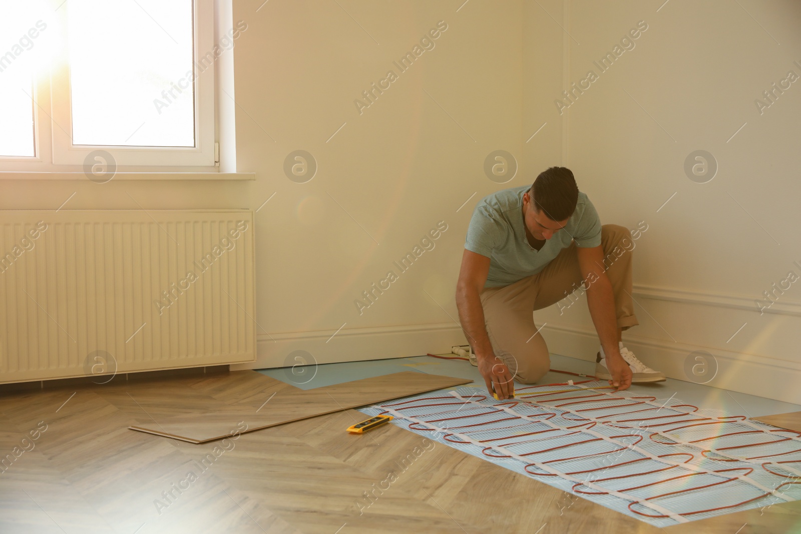 Photo of Professional worker installing electric underfloor heating system indoors