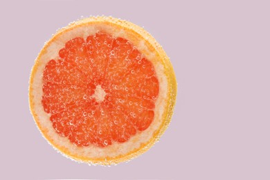 Photo of Slice of grapefruit in sparkling water on light background. Citrus soda