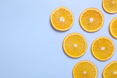 Photo of Slices of juicy orange on light blue background, flat lay. Space for text
