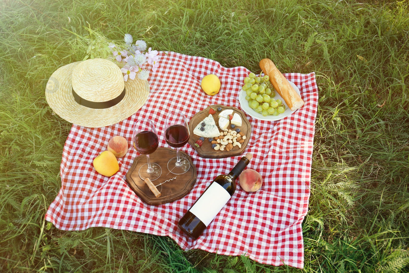 Photo of Picnic blanket with delicious food and wine on green grass in park