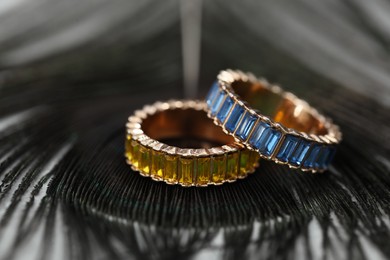 Two stylish rings and black feather on table, closeup