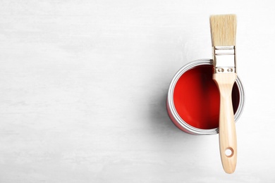 Photo of Can with red paint and brush on light background, top view. Space for text