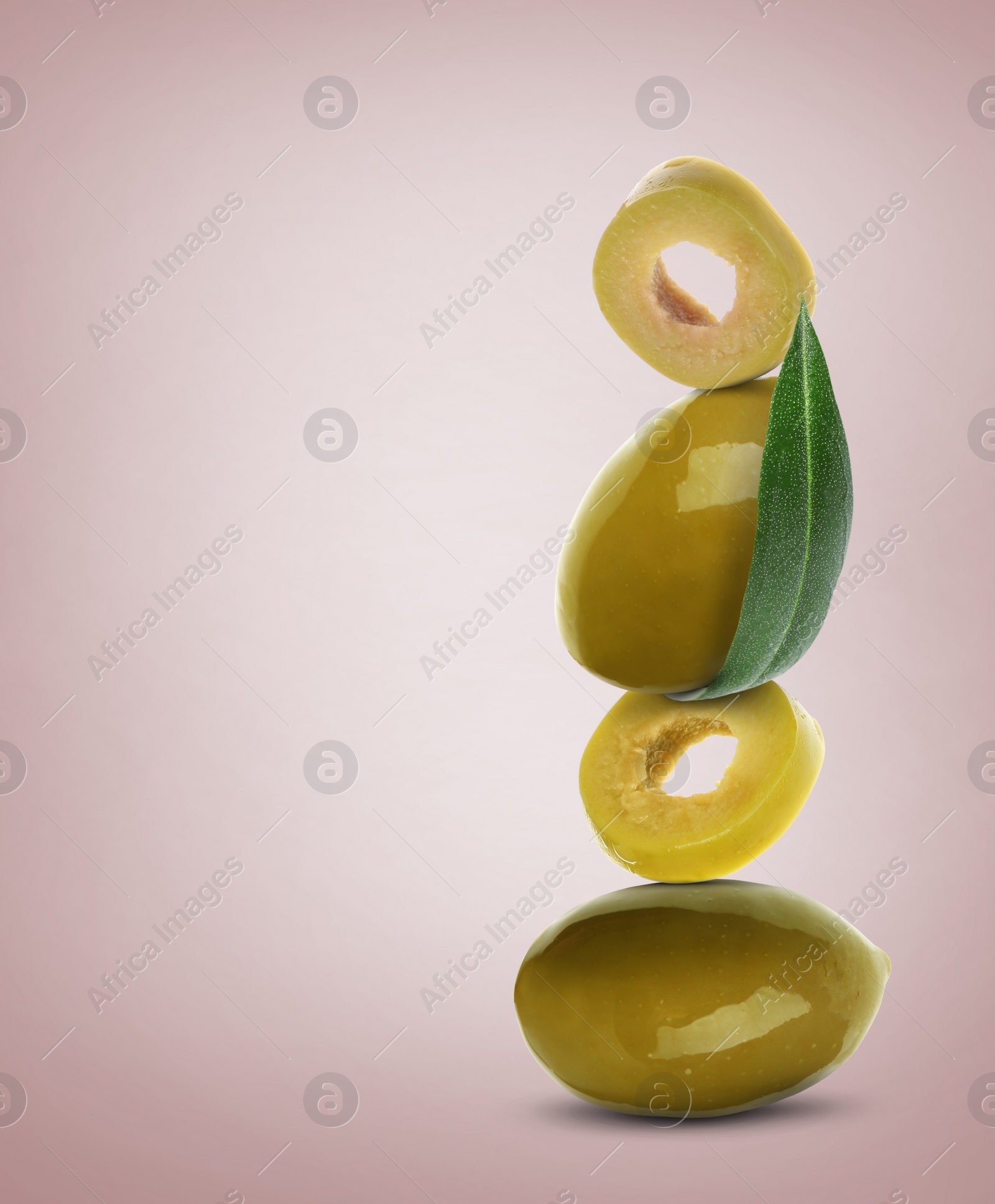 Image of Cut and whole olives with leaf on dusty pink background, space for text