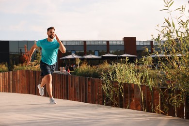 Photo of Smiling man running outdoors on sunny day. Space for text